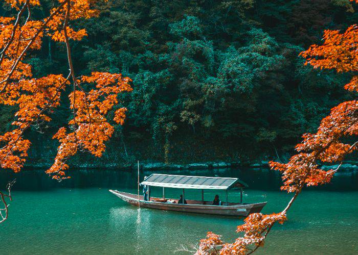 A covered river boat in Fushimi, framed by the eye-catching autumn leaves.